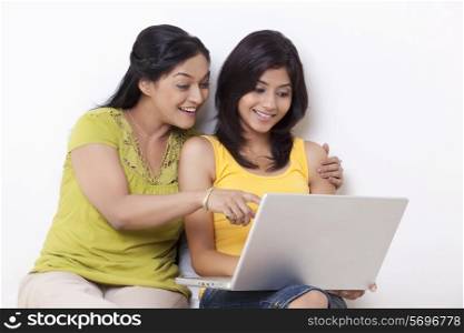 Mother and daughter using computer together over white background