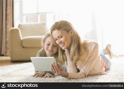 Mother and daughter using digital tablet on floor at home