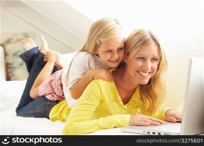 Mother And Daughter Using Laptop Relaxing Sitting On Sofa At Home