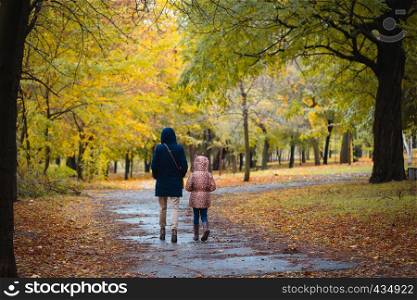 mother and daughter walking after the rain at the autumn park