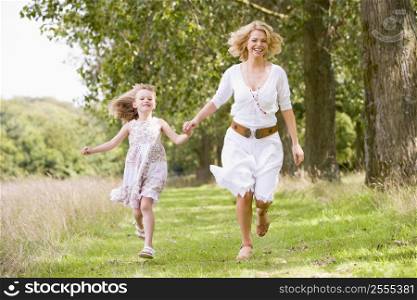 Mother and daughter walking on path holding hands smiling