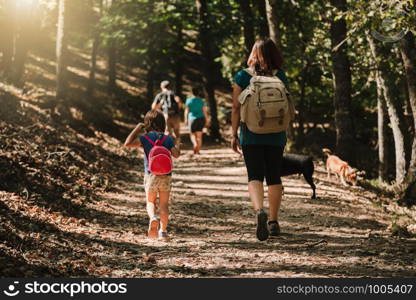 Mother and daughter walking trough a path with their dogs in the woods wearing backpacks and shorts