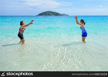 Mother and daughter wear a swimsuit playing in the blue sea near the beach with happiness during summer at Koh Miang Island, Mu Ko Similan National Park, Phang Nga province, Thailand