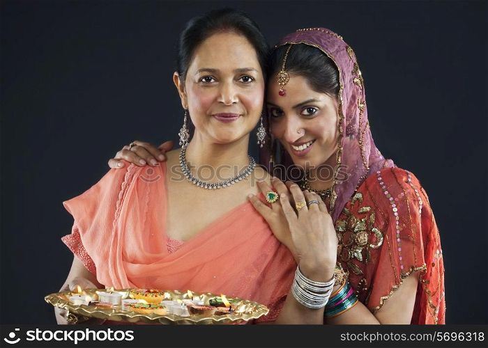 Mother and daughter with a tray of diyas