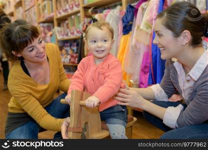 mother and daughter with attractive vendor in toy store