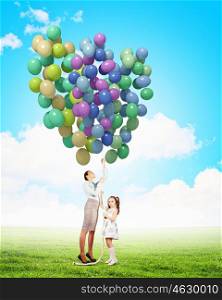 Mother and daughter with balloons. Image of little cute girl and mother with bunch of color balloons