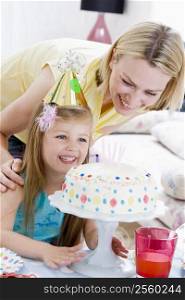 Mother and daughter with birthday cake smiling