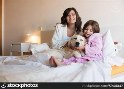 Mother and daughter with dog in bed
