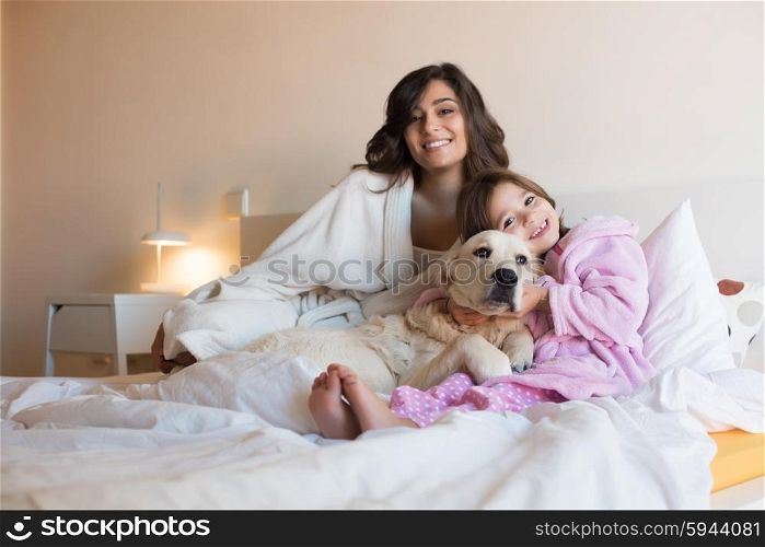 Mother and daughter with dog in bed