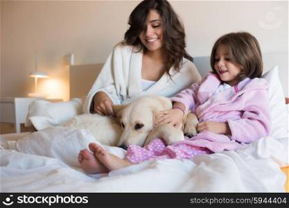 Mother and daughter with dog in bed - focus on dog