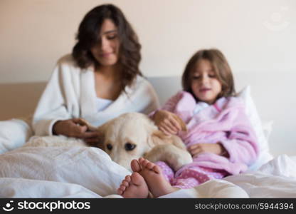 Mother and daughter with dog in bed - focus on feet