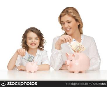 mother and daughter with piggy banks and paper money