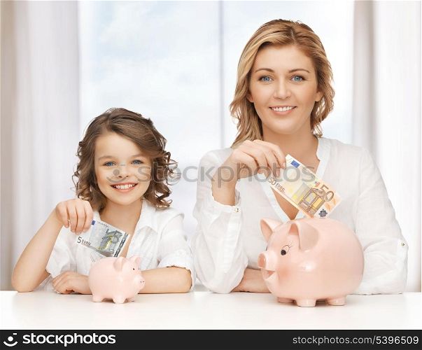 mother and daughter with piggy banks and paper money