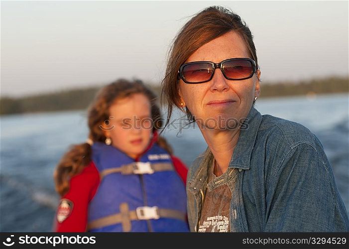 Mother and daughter with the sunlight in their face while riding in a boat at Lake of the Woods, Ontario