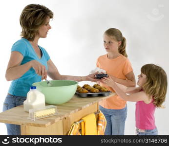 Mother and daughters baking blueberry muffins.