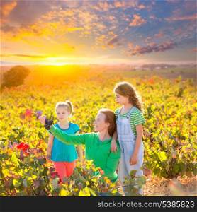 Mother and daughters family on autumn vineyard happy smiling holding grape bunch