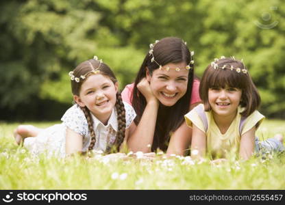 Mother and daughters lying outdoors with flowers smiling