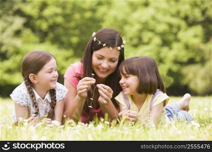 Mother and daughters lying outdoors with flowers smiling