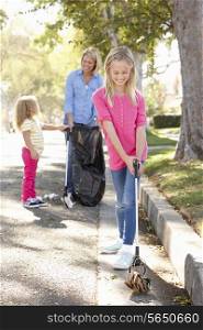 Mother And Daughters Picking Up Litter In Suburban Street