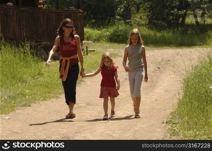 Mother and daughters walking down dirt road