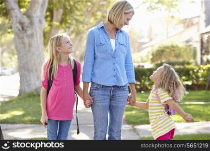Mother And Daughters Walking To School On Suburban Street