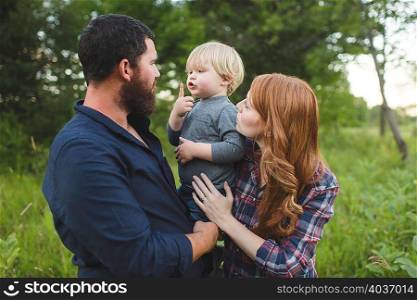 Mother and father holding young son, outdoors