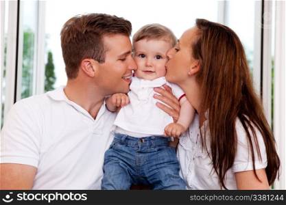 Mother and Father kissing their toddler son on the cheek