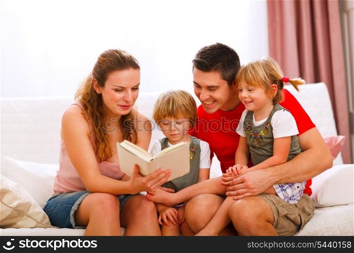 Mother and father reading to twins daughters&#xA;