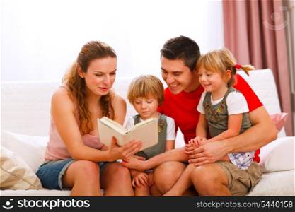 Mother and father reading to twins daughters&#xA;