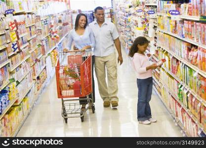 Mother and father with young daughter shopping at a grocery store.