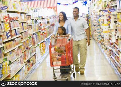 Mother and father with young daughter shopping at the grocery store.
