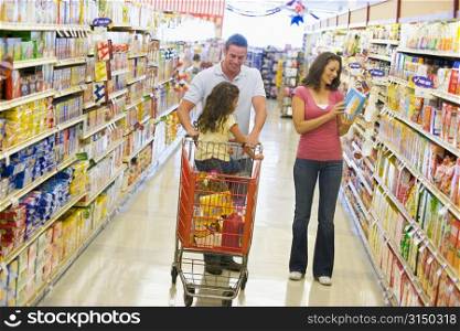 Mother and father with young daughter shopping at the grocery store.