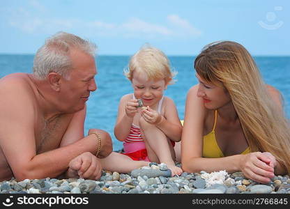 Mother and grandfather with child on sea coast