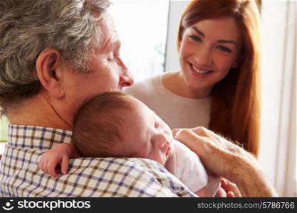 Mother And Grandfather With Sleeping Newborn Baby Daughter