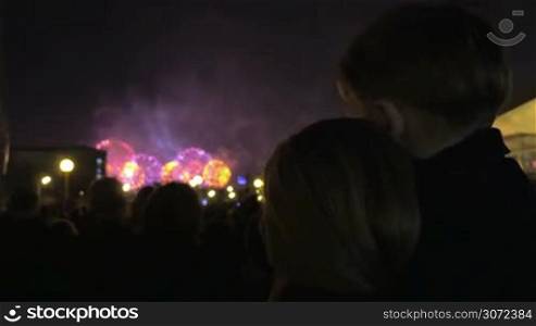 Mother and her little son are watching fireworks, she&acute;s carrying the child in her arms.