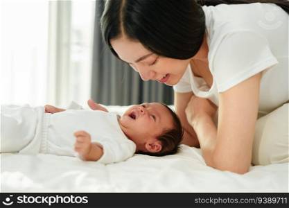 mother and her newborn baby lying and playing on a bed