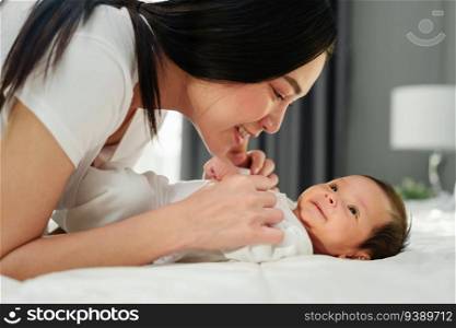 mother and her newborn baby lying and playing on a bed