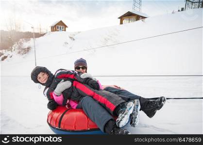 Mother and her son on a snow tube, at beauty winter day