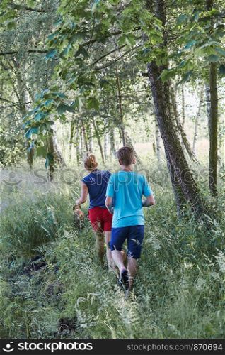 Mother and her son walking along a path, among the trees, close to nature, during summer vacations. Candid people, real moments, authentic situations