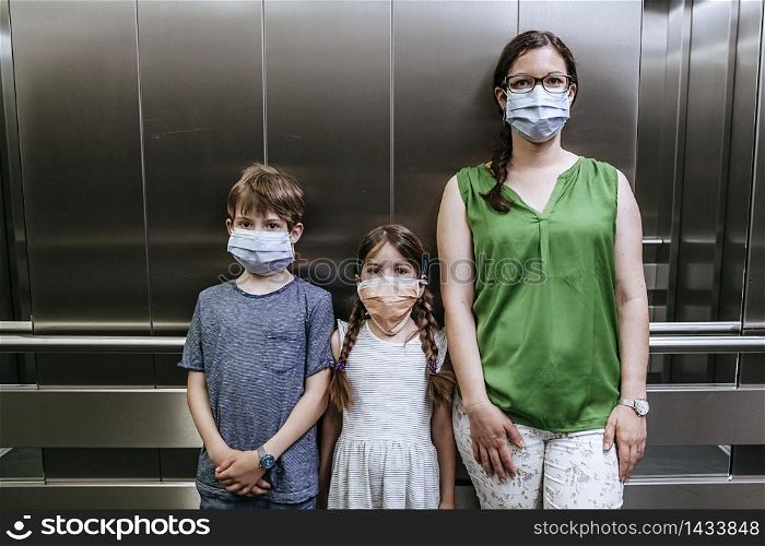 Mother and her two children wearing protective masks during covid-19 pandemic.
