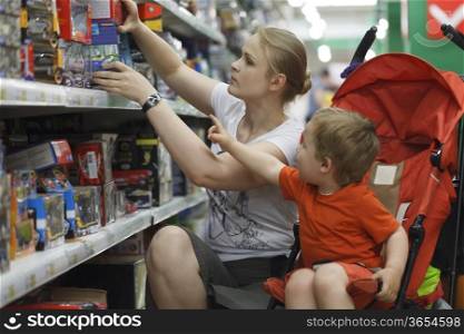 Mother and her two year old son are shopping for toys