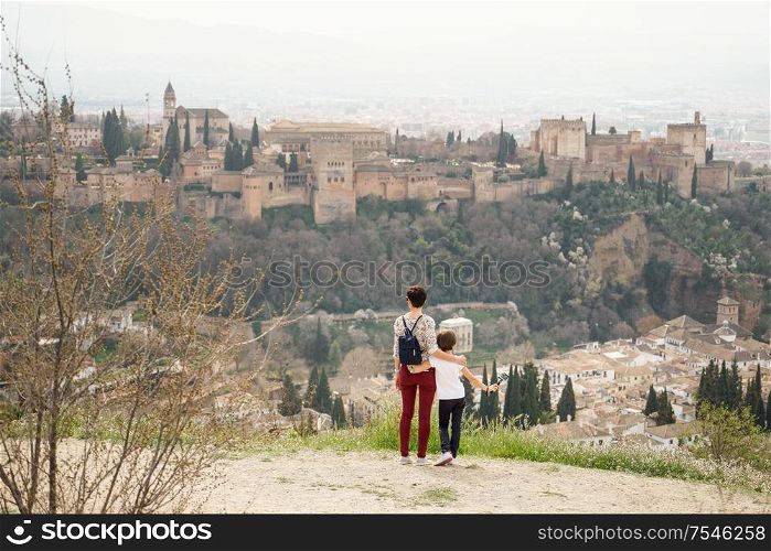 Mother and little daughter looking at the Alhambra of Granada from Cerro de San Miguel. Single parent family doing tourism.. Mother and little daughter looking at the Alhambra
