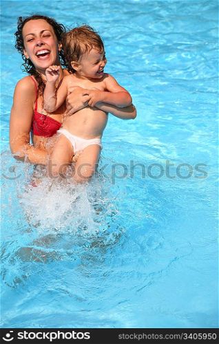 Mother and little daughter playing in pool
