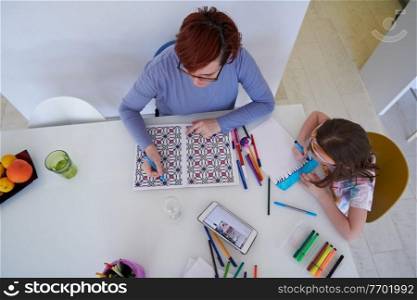 Mother and little daughter  playing together  drawing creative artwork during coronavirus quarantine measuring time on sandglass and listening music on tablet