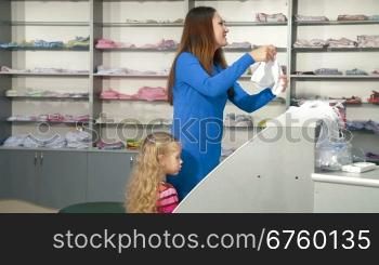 Mother and little daughter shopping for girls clothes in a clothing store, looking kids underwear