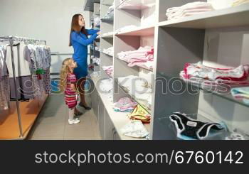 Mother and little daughter shopping for girls clothes in a clothing store, looking kids underwear