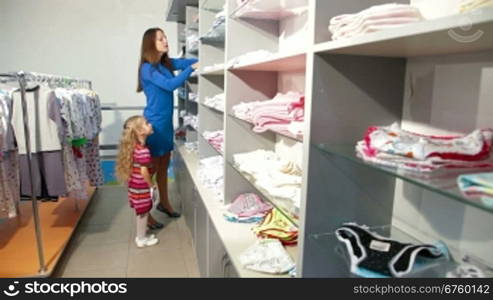 Mother and little daughter shopping for girls clothes in a clothing store, looking kids underwear