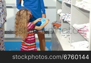Mother and little daughter shopping for girls clothes in a clothing store, looking kids underwear. Medium shot