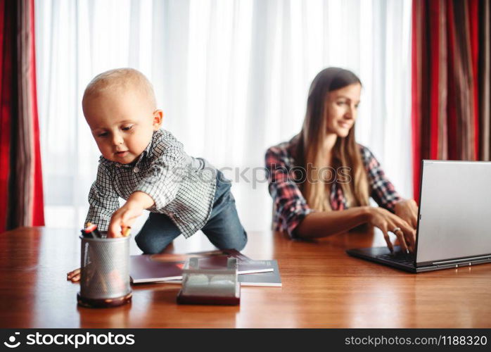 Mother and little kid looks on laptop screen. Mom and son happy together at home. Mother and little kid looks on laptop screen