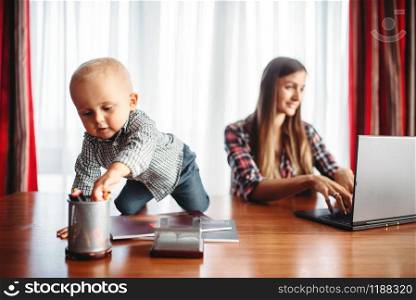 Mother and little kid looks on laptop screen. Mom and son happy together at home. Mother and little kid looks on laptop screen